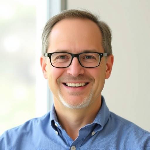 Headshot of John Smith, smiling and wearing glasses and a button-down shirt.